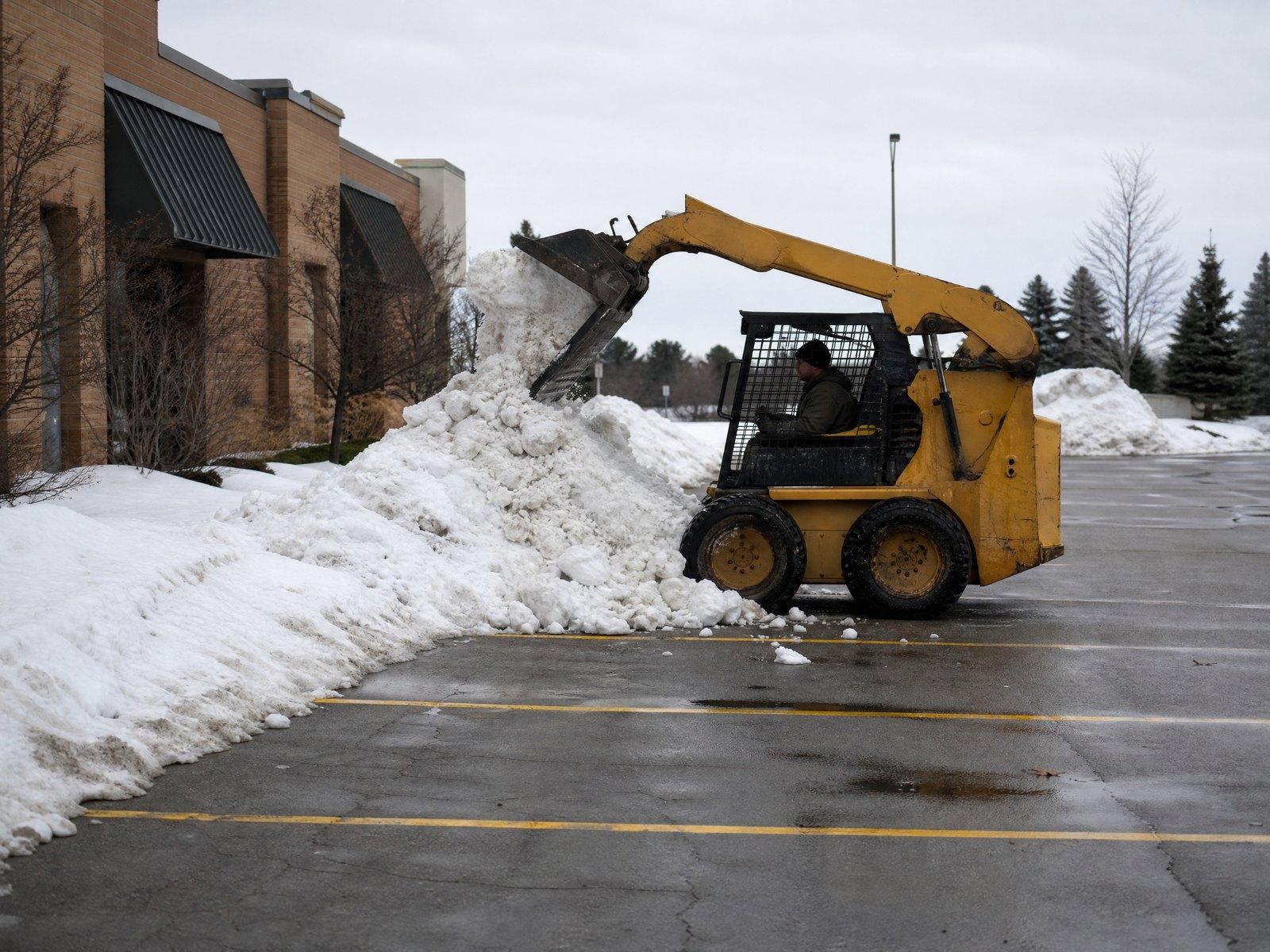 Loader stacking snow at the edge of a lot